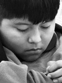 a young boy with his eyes closed is holding a small object