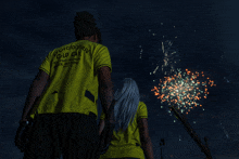 a man wearing a yellow shirt that says old car is watching fireworks