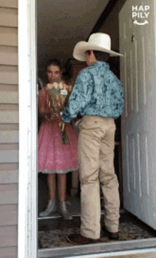 a man in a cowboy hat holds a bouquet of flowers in front of a door that says hap pily