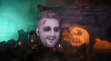 a man with halloween makeup on his face is smiling in front of a pumpkin .