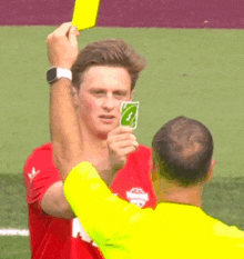 a man in a red shirt is holding a uno card and a yellow card