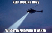 a helicopter is flying in the sky with a light shining out of it .