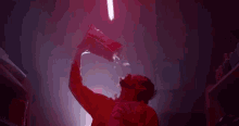 a man is drinking water from a bag in a dark room with red lights .