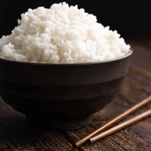 a bowl of white rice next to chopsticks on a table