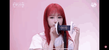 a girl with red hair is holding a device in front of her ears