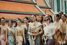 a group of women posing for a photo with one wearing a sash that says macau on it