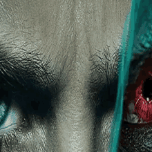 a close up of a person 's face with a bloody eye and a green background .