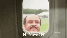 a man with a mustache is smiling while looking out of an airplane window and says hi simon .