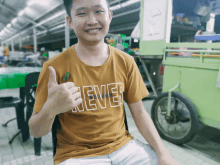 a young man wearing a yellow shirt that says never gives a thumbs up