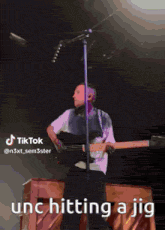 a man playing a guitar and singing into a microphone with a caption that says tiktok unc hitting a jig