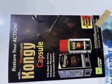 a bottle of kongy capsules sits on top of a poster that says restore your action