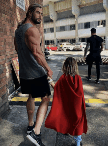 a man holding a child 's hand while wearing a cape that says thor