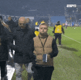a group of people walking on a soccer field with the espn logo on the wall behind them