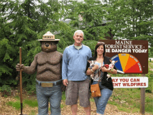 a man and a woman standing next to a smokey bear statue