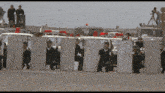 a group of police officers standing in front of a row of riot shields with the number 11 on them