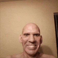 a bald man is smiling for the camera while taking a selfie .