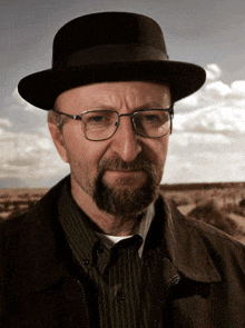 a man wearing a hat and glasses looks at the camera