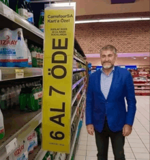 a man in a blue jacket is standing in front of a yellow sign that says 6 al 7 ode