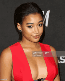 a woman in a red dress with a plunging neckline and earrings