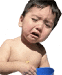 a shirtless toddler is crying while holding a blue cup .