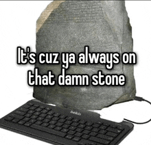 a belkin keyboard sits in front of a large rock that says " it 's cuz ya always on that damn stone "