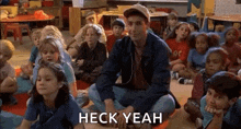a group of children are sitting on the floor in a classroom with a man sitting on the floor .