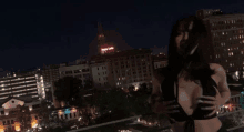 a woman stands on a balcony overlooking a city at night with a building that says temple lofts in the background