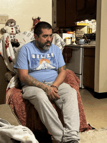 a man in a belize shirt sits on a chair