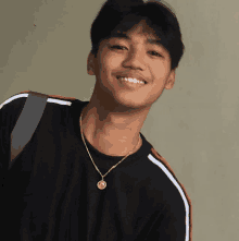 a young man wearing a black shirt and a gold necklace