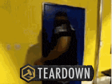 a man is standing in front of a yellow wall with a sign that says teardown
