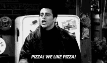 a man in a leather jacket is standing in front of a refrigerator and shouting pizza ! we like pizza !