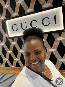 a woman is smiling in front of a sign that says gucci