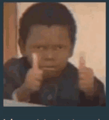 a young boy is giving a thumbs up sign while making a funny face .