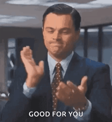 a man in a suit and tie is clapping his hands and says good for you .