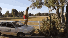 a man standing on the hood of a white car with a license plate that says ' sydney ' on it