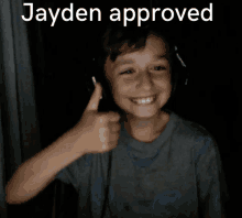 a young boy wearing headphones is smiling and giving a thumbs up with the words jayden approved behind him