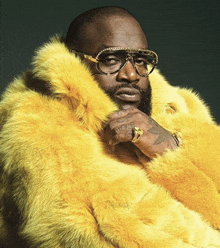 a man is wearing a yellow fur coat and sunglasses