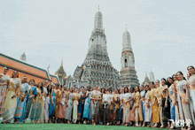 a group of women are posing in front of a temple and the word mcvs is on the bottom right