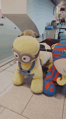 a stuffed animal that looks like a minion is sitting on a tile floor