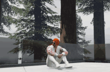 a man with red hair sits on the ground in front of a forest