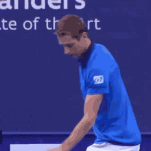 a man in a blue shirt is standing on a tennis court in front of a sign that says landers