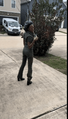 a woman standing on a sidewalk holding a drink