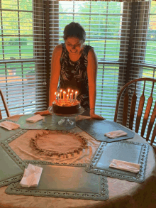 a woman stands in front of a birthday cake with candles on it