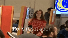 a woman in a red sweater is standing in front of a group of people with the words `` rolls reset soon '' .