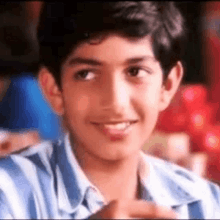 a young boy wearing a blue and white striped shirt is smiling .