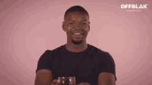 a man in a black shirt holds a glass of red liquid in front of a pink background that says offblok