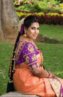 a woman wearing a purple blouse with elephants on it sits in the grass