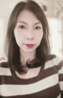 a woman wearing a striped shirt with red lipstick on her lips