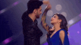 a man and a woman are dancing together on a stage and the woman is wearing a blue dress .
