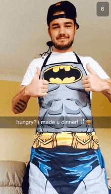 a man wearing a batman apron giving two thumbs up